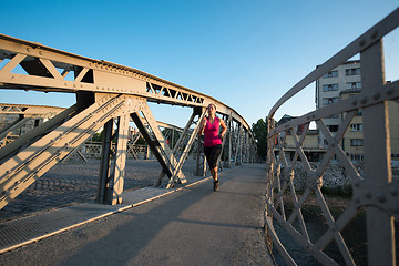 Image showing woman jogging across the bridge at sunny morning