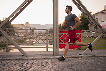 Image showing man jogging across the bridge at sunny morning