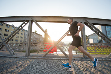 Image showing man jogging across the bridge at sunny morning