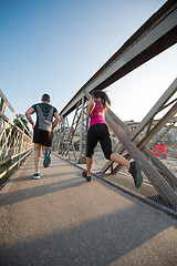 Image showing young couple jogging across the bridge in the city