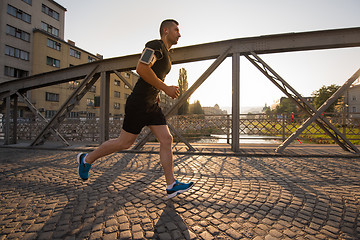 Image showing man jogging across the bridge at sunny morning