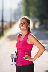Image showing woman drinking water from a bottle after jogging
