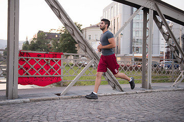 Image showing man jogging across the bridge at sunny morning