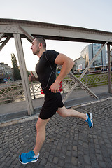 Image showing man jogging across the bridge at sunny morning