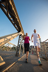 Image showing young couple jogging across the bridge in the city