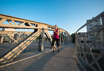 Image showing woman jogging across the bridge at sunny morning