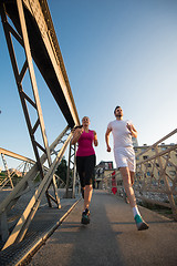 Image showing young couple jogging across the bridge in the city