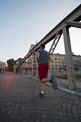 Image showing man jogging across the bridge at sunny morning