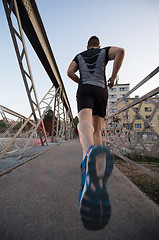 Image showing man jogging across the bridge at sunny morning