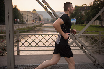 Image showing man jogging across the bridge at sunny morning