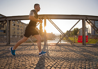 Image showing man jogging across the bridge at sunny morning