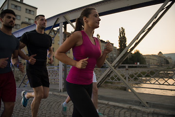 Image showing group of young people jogging across the bridge