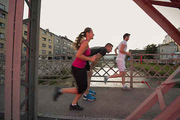 Image showing group of young people jogging across the bridge