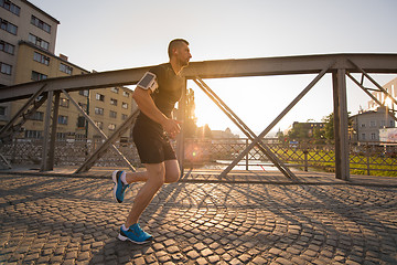 Image showing man jogging across the bridge at sunny morning