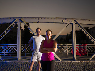 Image showing portrait of couple jogging across the bridge in the city