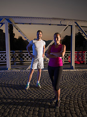 Image showing portrait of couple jogging across the bridge in the city