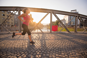 Image showing woman jogging across the bridge at sunny morning