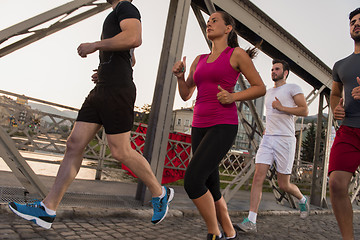 Image showing group of young people jogging across the bridge