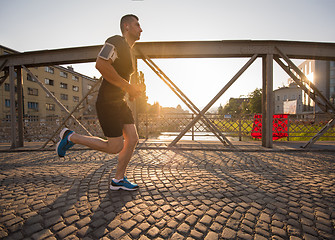 Image showing man jogging across the bridge at sunny morning