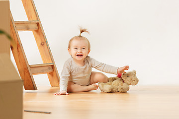 Image showing Friendly blue eyed baby girl sitting on the floor indoors