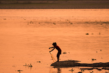 Image showing Asian Woman fishing in the river, silhouette at sunset