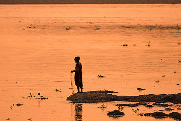 Image showing Asian Woman fishing in the river, silhouette at sunset