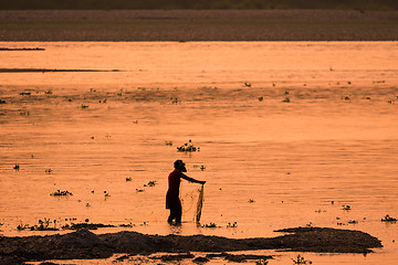 Image showing Asian Woman fishing in the river, silhouette at sunset