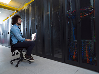 Image showing engineer working on a laptop in server room