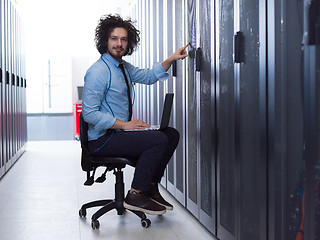 Image showing engineer working on a laptop in server room