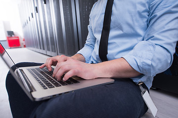 Image showing engineer working on a laptop in server room