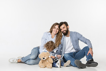 Image showing Smiling family sitting together in studio and watching their favorite cartoons on laptop