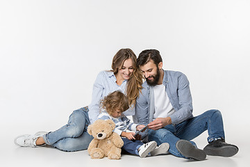 Image showing Smiling family sitting together in studio and watching their favorite cartoons on laptop