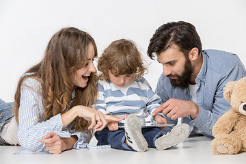 Image showing Smiling family sitting together in studio and watching their favorite cartoons on laptop