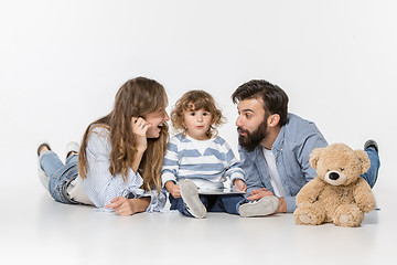 Image showing Smiling family sitting together in studio and watching their favorite cartoons on laptop