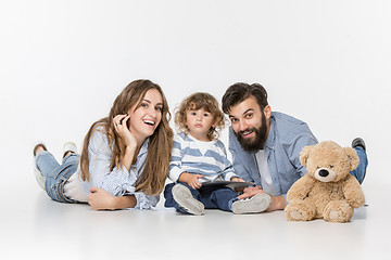 Image showing Smiling family sitting together in studio and watching their favorite cartoons on laptop