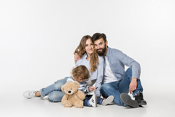 Image showing Smiling family sitting together in studio and watching their favorite cartoons on laptop