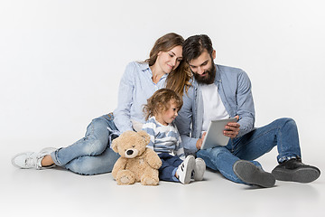 Image showing Smiling family sitting together in studio and watching their favorite cartoons on laptop