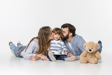 Image showing Smiling family sitting together in studio and watching their favorite cartoons on laptop