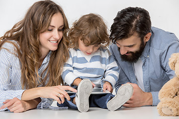 Image showing Smiling family sitting together in studio and watching their favorite cartoons on laptop