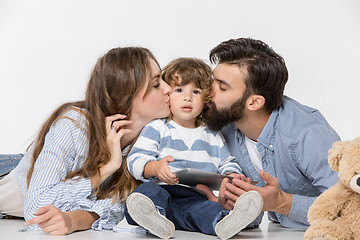 Image showing Smiling family sitting together in studio and watching their favorite cartoons on laptop