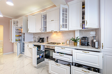 Image showing Modern white kitchen interior with open doors and drawers