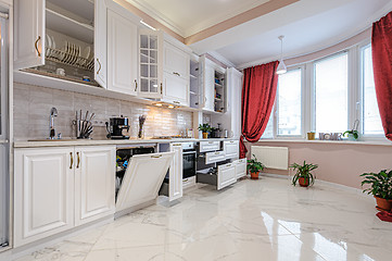 Image showing Luxury modern white kitchen interior with open doors and drawers