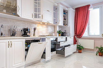 Image showing Luxury modern white kitchen interior with open doors and drawers