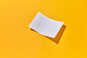 Image showing Sheet of blank paper with hard shadows on an yellow.