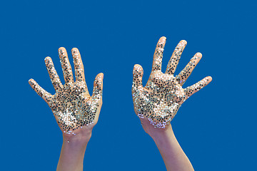 Image showing Woman\'s hands with holiday decoration glitter small stars on a blue.