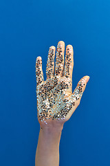 Image showing Girl\'s hand with glitter silver small stars on a blue background.