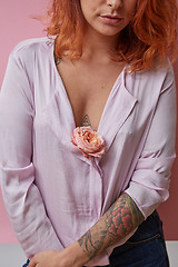 Image showing Sexual  girl with fresh flower living coral color in hands with tattoo on a gray background. 