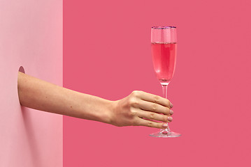 Image showing Woman\'s hand holds glass of rose wine with soft shadows.