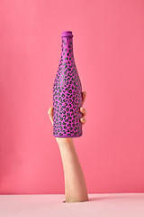 Image showing Painted hot pink wine bottle with black spots on a pink background.