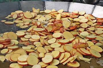 Image showing A lot of sliced potato slices are fried in big steel pan